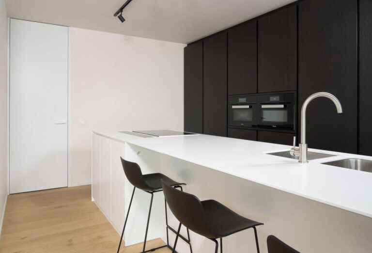 witte blokdeur tot aan het plafond in het wit zwarte keuken, heel modern