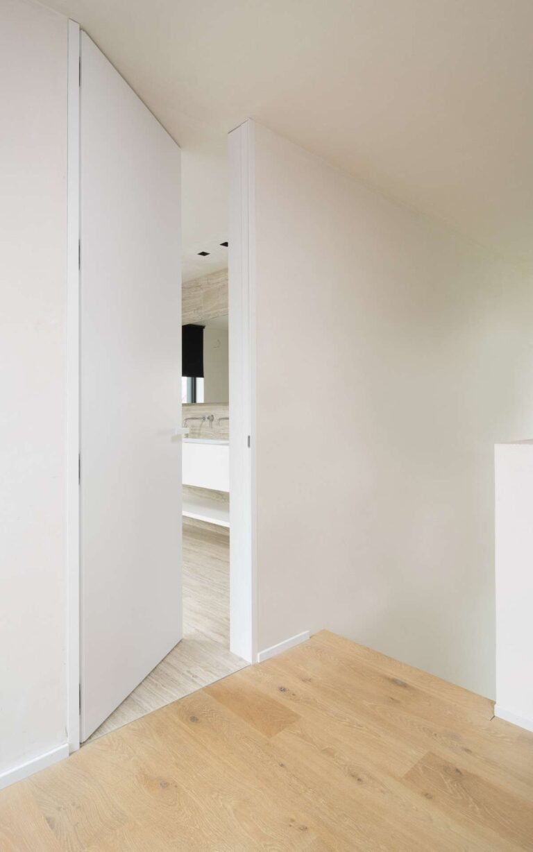 Moderne witte deur met witte deurklink die open is