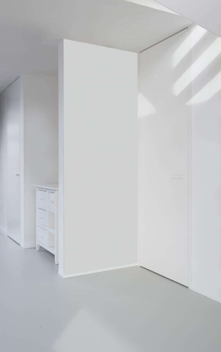 witte deur onder een trap gezien van de zijkant, plafondhoog