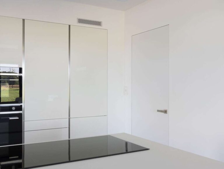 Moderne witte deur met zilveren deurklink in een keuken