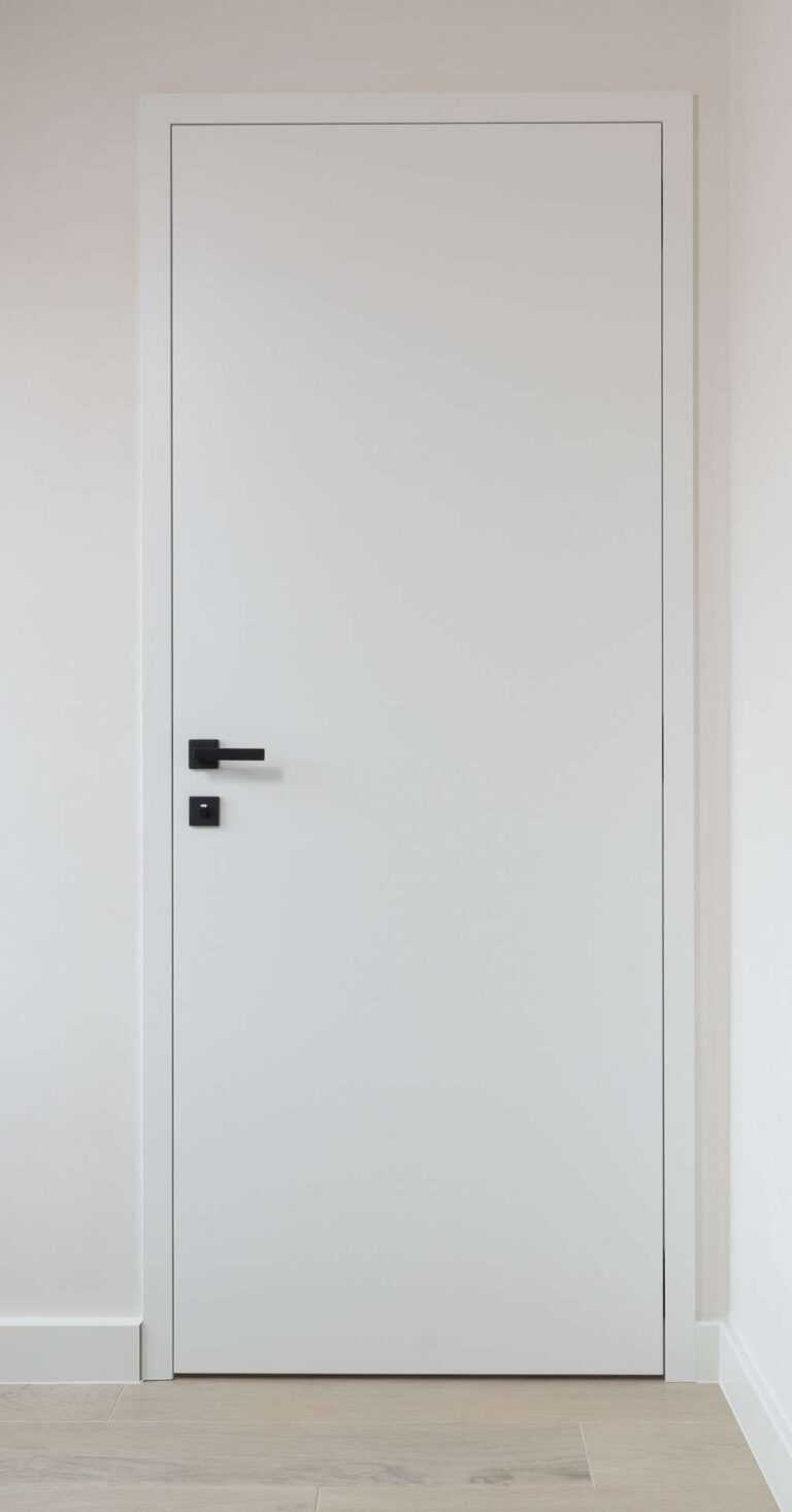 Witte gesloten houten binnendeur met een zwarte deurklink