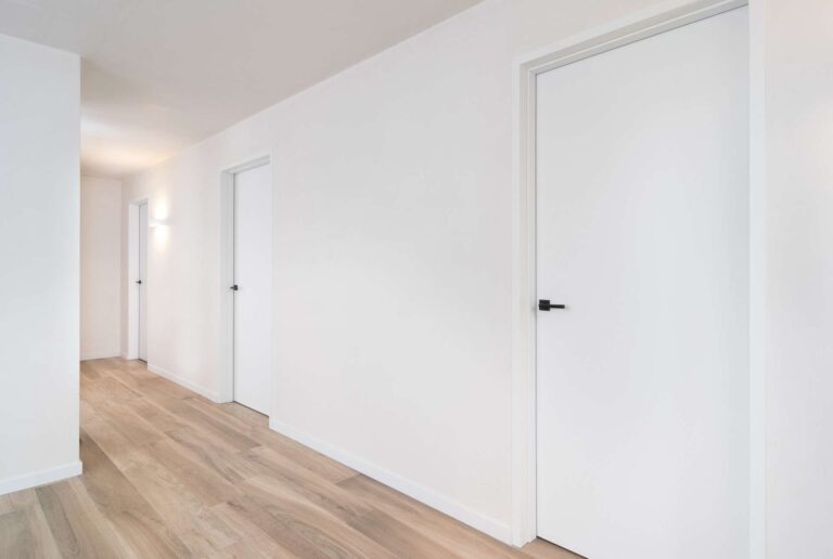 prachtige witte binnendeuren met zwarte handgrepen, afgewerkt met een laminaat vloer