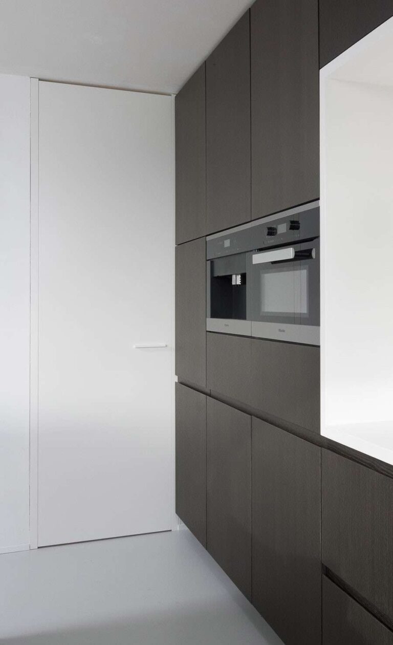 Witte hoge binnendeur in een keuken met zwarte kastdeuren